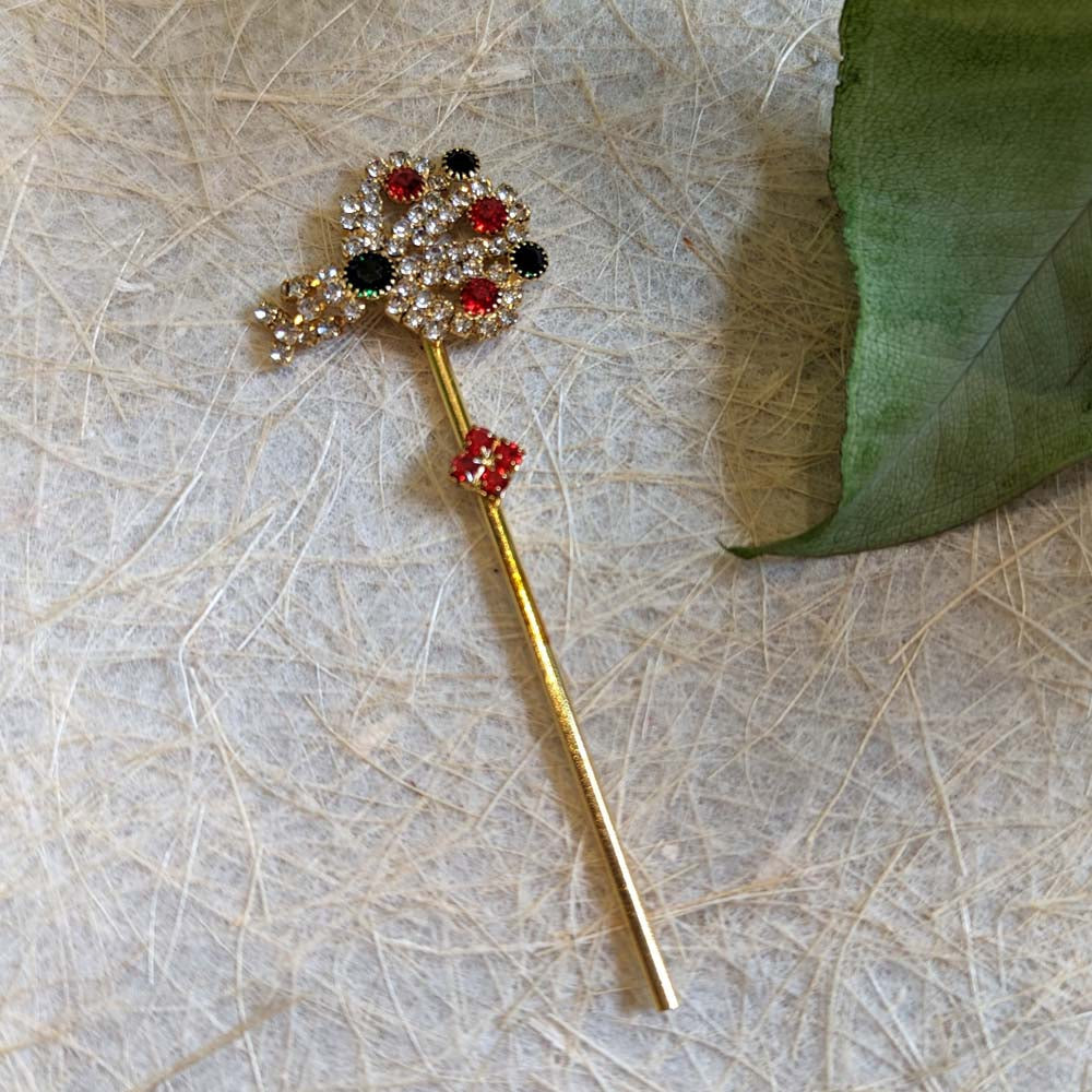 Golden Krishna flute with floral embellishments in red, black, and crystal-white stones.