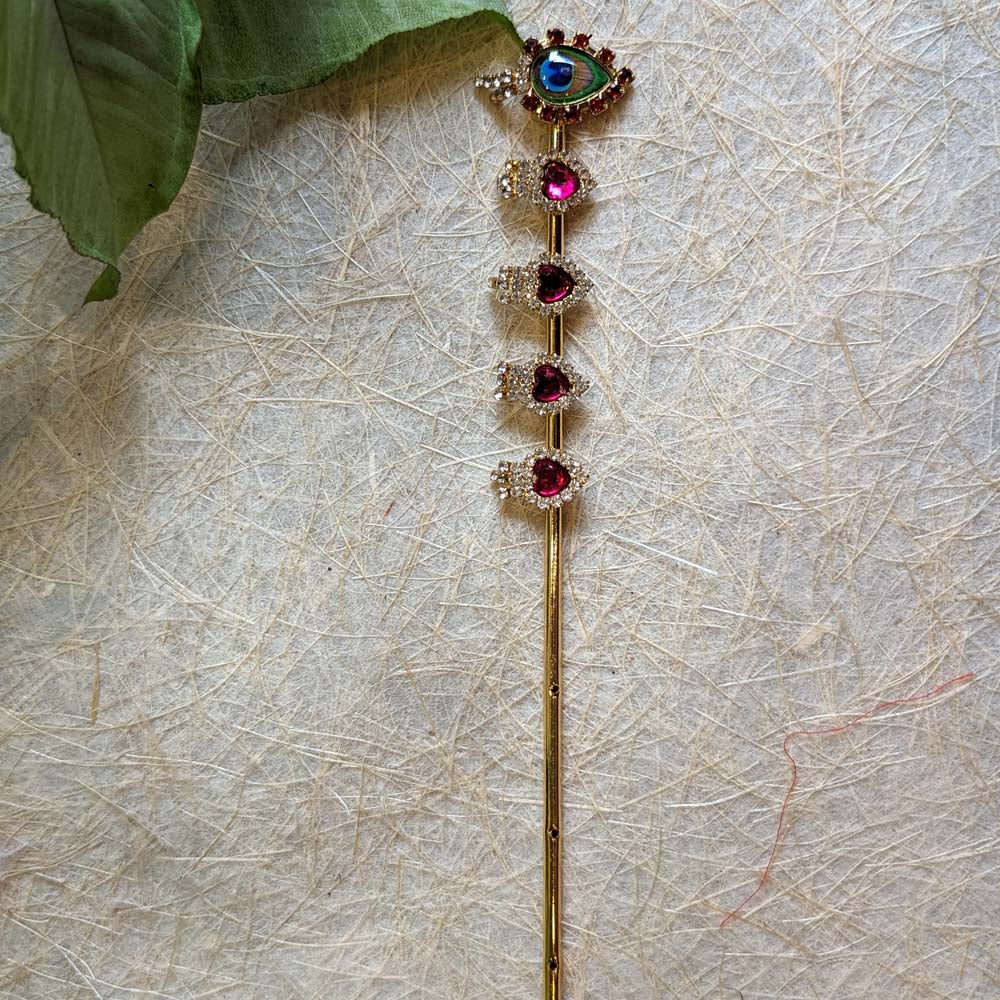 Golden Krishna flute with red butis and a decorative eye motif at the top.