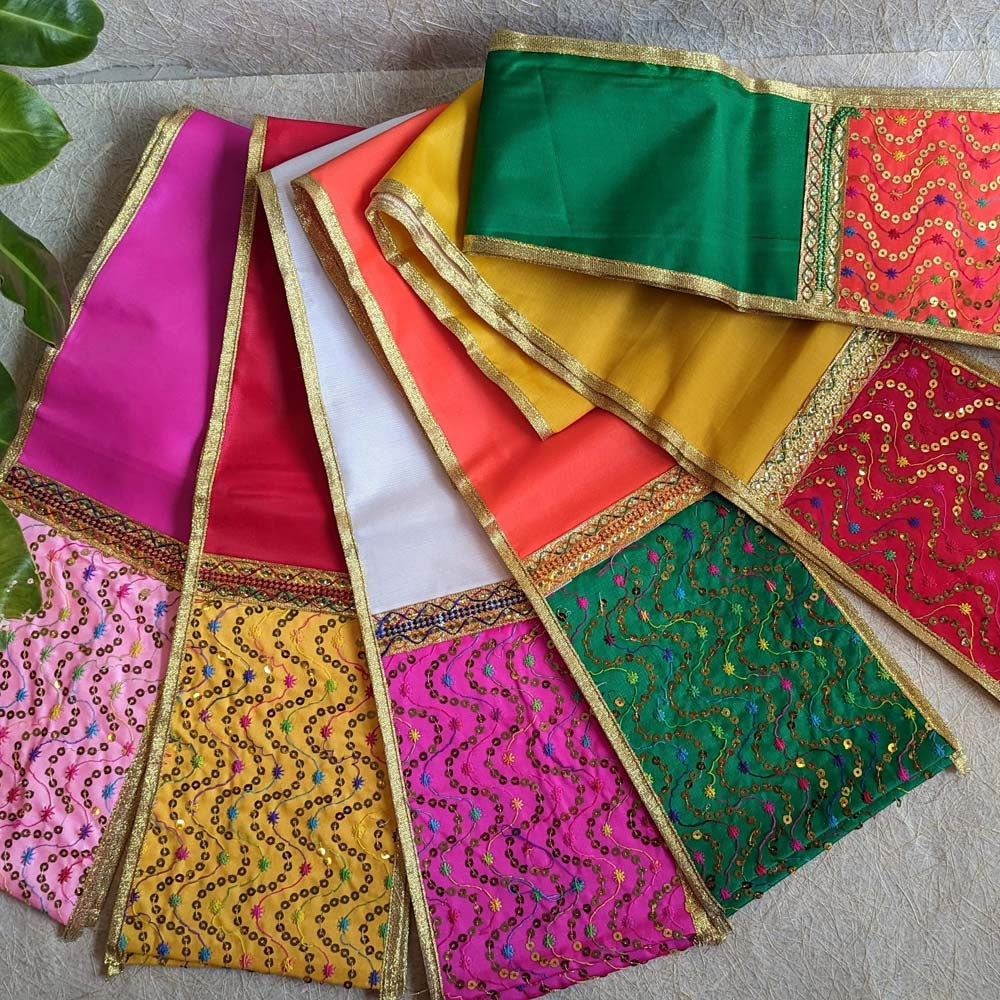 A vibrant Yellow Dupatta with red and gold embellishments, bordered with gold trims, displayed alongside other colorful designs on a textured background.
