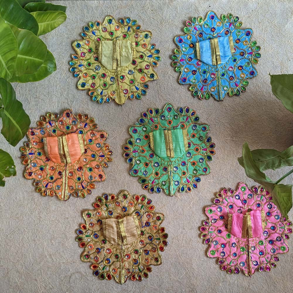 A beautifully designed Cream Lalji Vastra with a 6-inch peacock-inspired pattern, featuring colorful stones and golden accents, ideal for deity decoration.