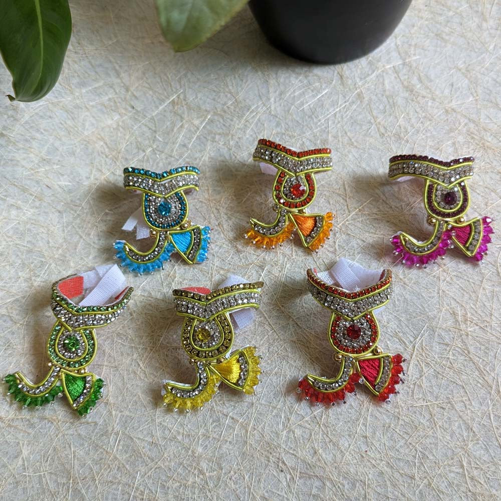 A traditional 2-inch Zardozi Mukut with intricate embroidery, vibrant colors, and stone embellishments, displayed on a textured background.