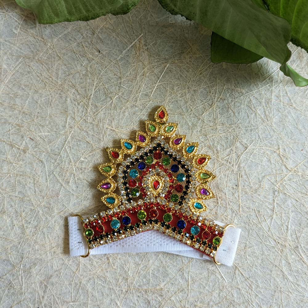 A 4-inch multicolor stone-studded Mukut with intricate gold detailing, displayed on a textured background, perfect for deity adornment.