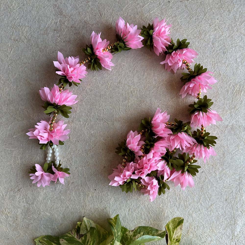 Pink artificial floral garland with green leaves and gold bead accents, ideal for festive and wedding decor.