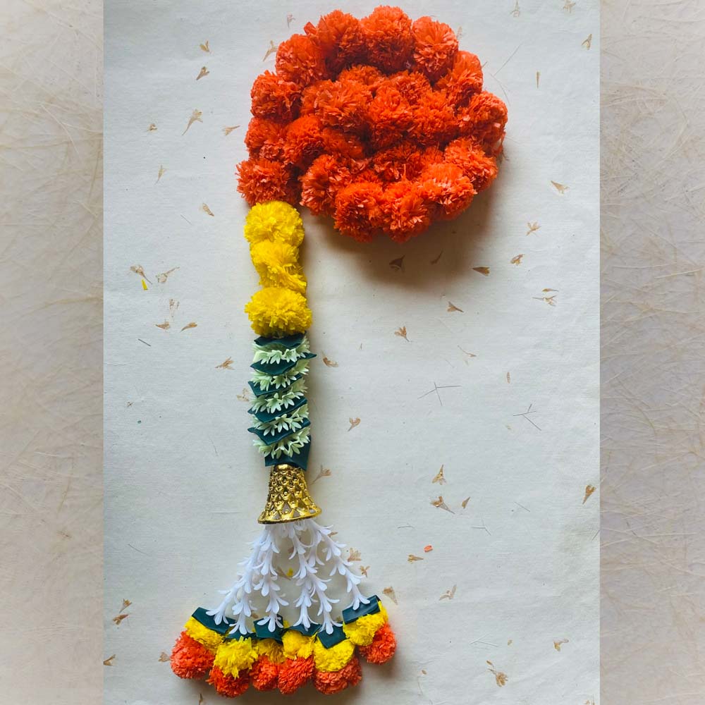 Artificial marigold garland with orange and yellow flowers, green and white accents, and a decorative gold bell with tassels.