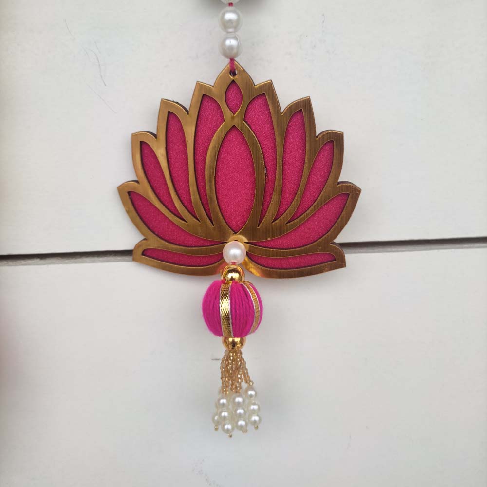 A vibrant pink and gold lotus-shaped hanging decor with intricate detailing, adorned with pearls and a tassel finish.