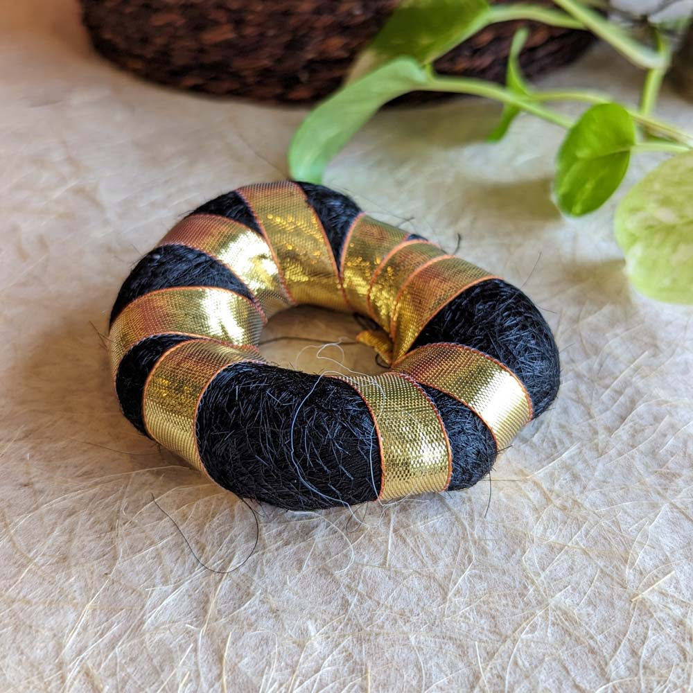 Soft black hair bun ring with golden ribbon accents for traditional and festive hairstyles