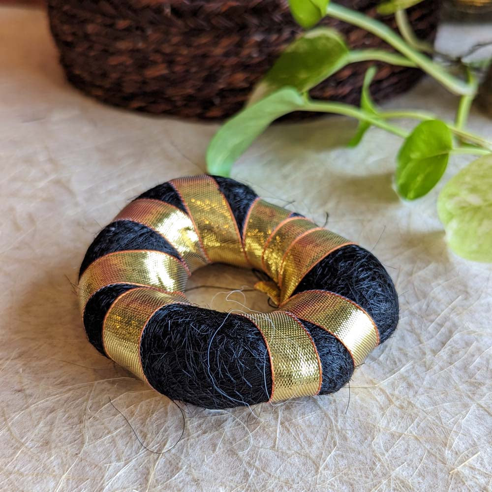 Soft Hair Bun Maker wrapped in black fibers and golden ribbon for traditional hairstyles
