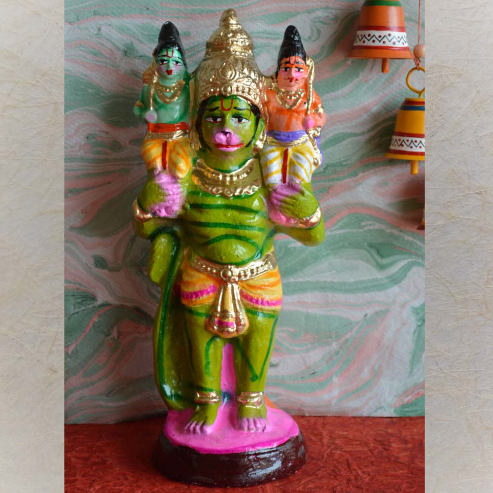 Handcrafted Golu doll depicting Lord Rama, Lakshmana, and Hanuman in a standing pose with vibrant green, orange, and gold hues, set against a decorative background.