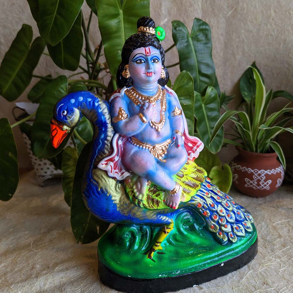 Handcrafted Peacock with Baby Krishna Golu Doll, vibrant and intricately painted, showcasing traditional Indian artistry.