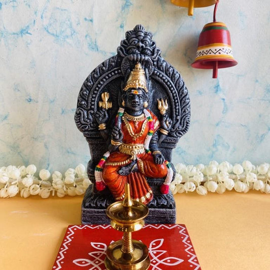 Thiruvatchi Mariamman Golu doll with a black stone-like textured base and vibrant red and green attire adorned with gold details.