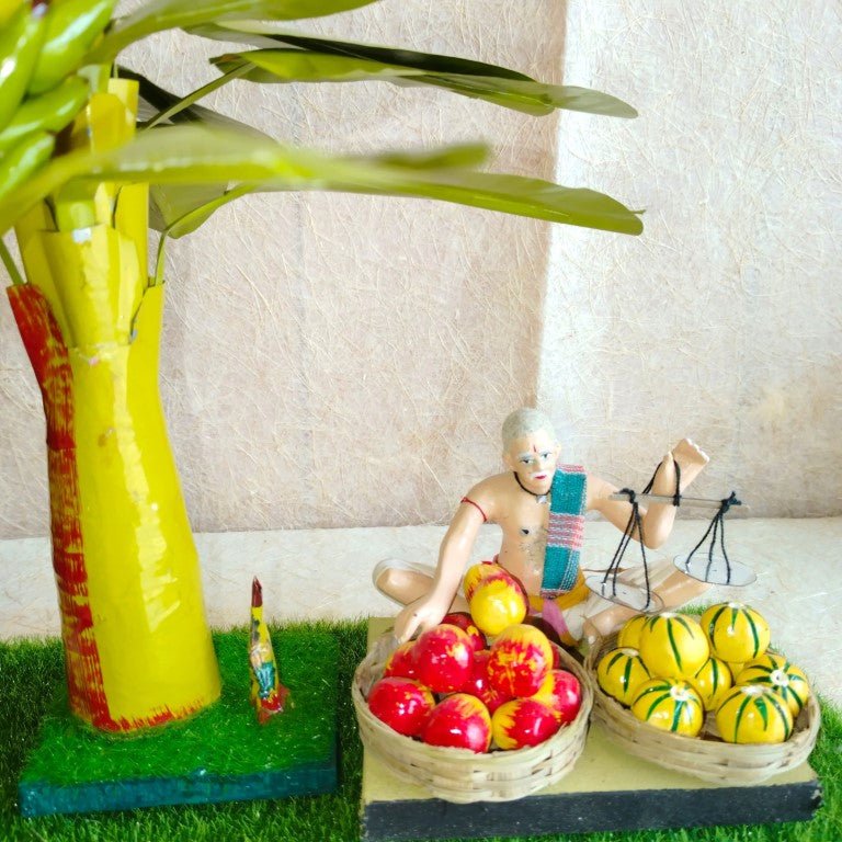 Navarathri Golu Vendor Fruit Seller doll set featuring a vendor with a weighing scale, baskets of yellow and red fruits, and a banana tree.
