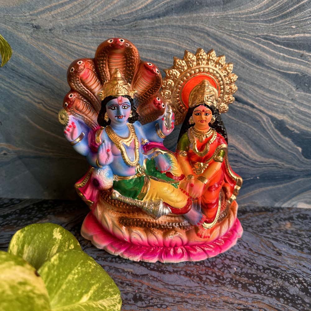Handcrafted Lakshmi Narayana idol featuring Vishnu reclining on Sheshnag and Lakshmi seated beside him, adorned with vibrant colors and intricate details.