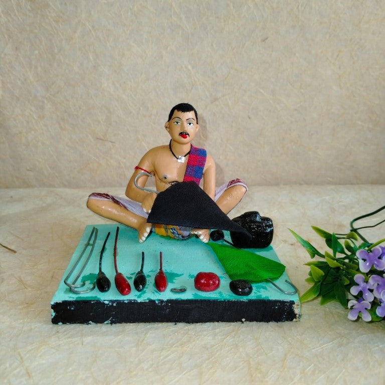Handcrafted Golu doll depicting a traditional Indian umbrella maker surrounded by tools and crafting materials.