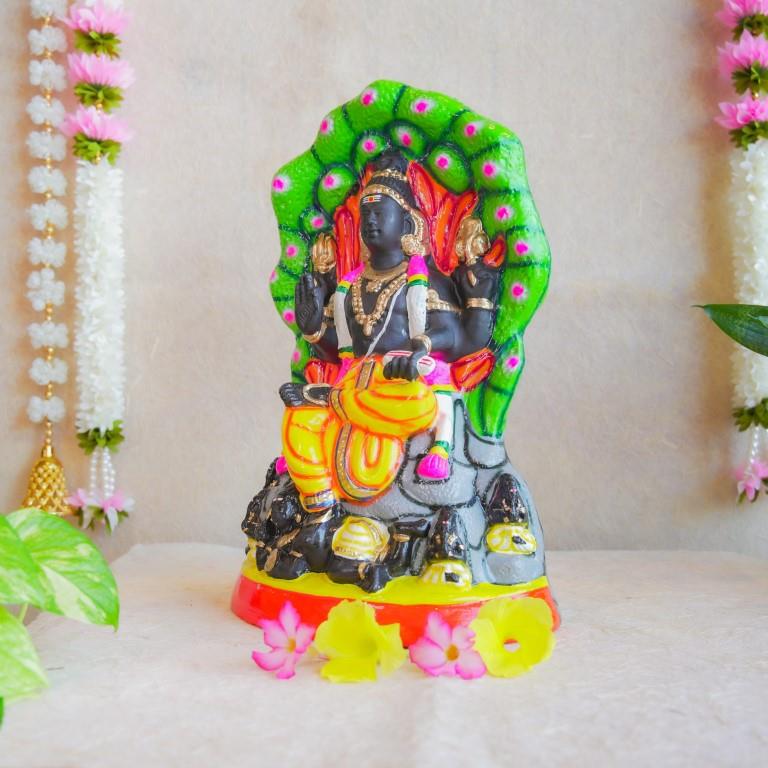 Handcrafted Navarathri Golu doll depicting Lord Dakshinamoorthy seated under a serpent canopy with vibrant detailing.