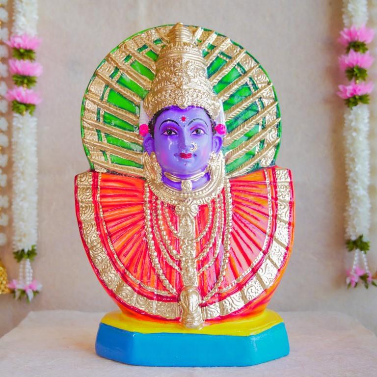 Handcrafted Navarathri Golu doll of Goddess Renugammal with a vibrant gold and green decorative backdrop.