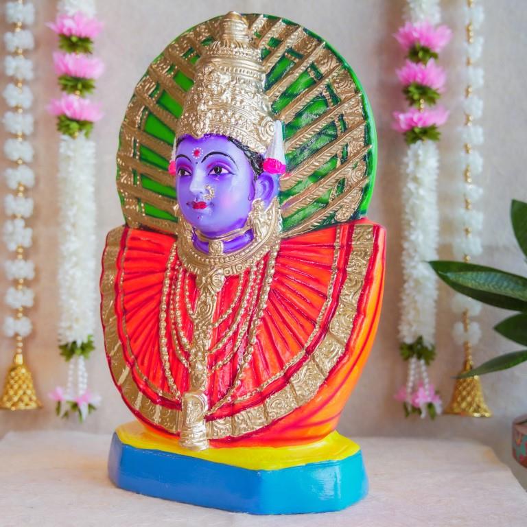 Handcrafted Navarathri Golu doll of Goddess Renugammal with a vibrant gold and green decorative backdrop.