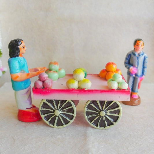 Navarathri Golu Dolls showcasing a vegetable vendor with a pink cart filled with colorful produce and a female figure standing nearby.