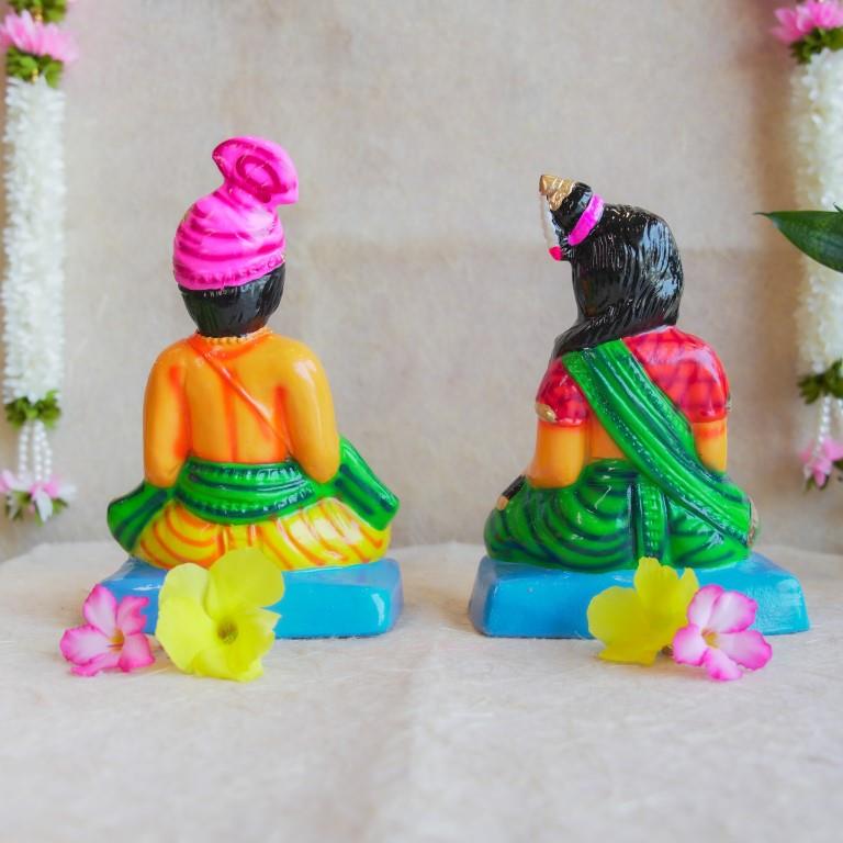 Navarathri Golu dolls depicting a seated Mama and Mami, dressed in traditional attire with vibrant colors, sitting on blue bases.