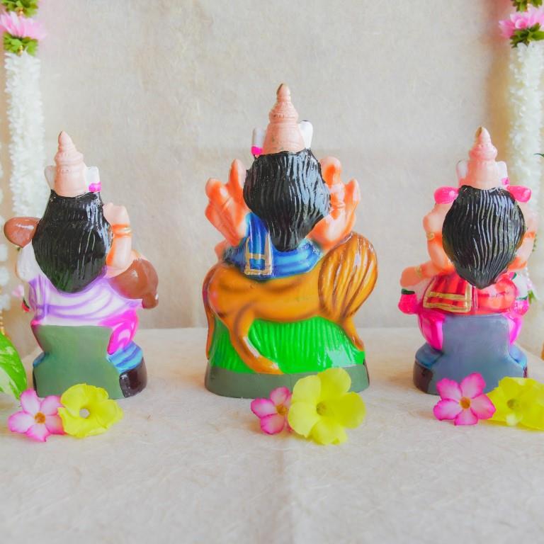 Handcrafted Navarathri Golu dolls of Durga, Lakshmi, and Saraswathi, beautifully painted and displayed with floral decorations.
