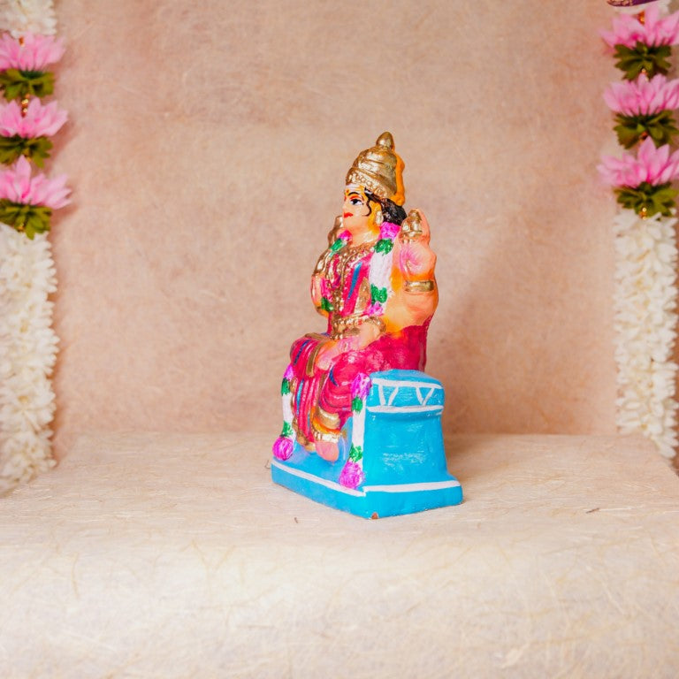 Hand-painted Navarathri Golu doll of Goddess Karumari Amman in a colorful seated posture with intricate detailing and vibrant pink and gold hues.
