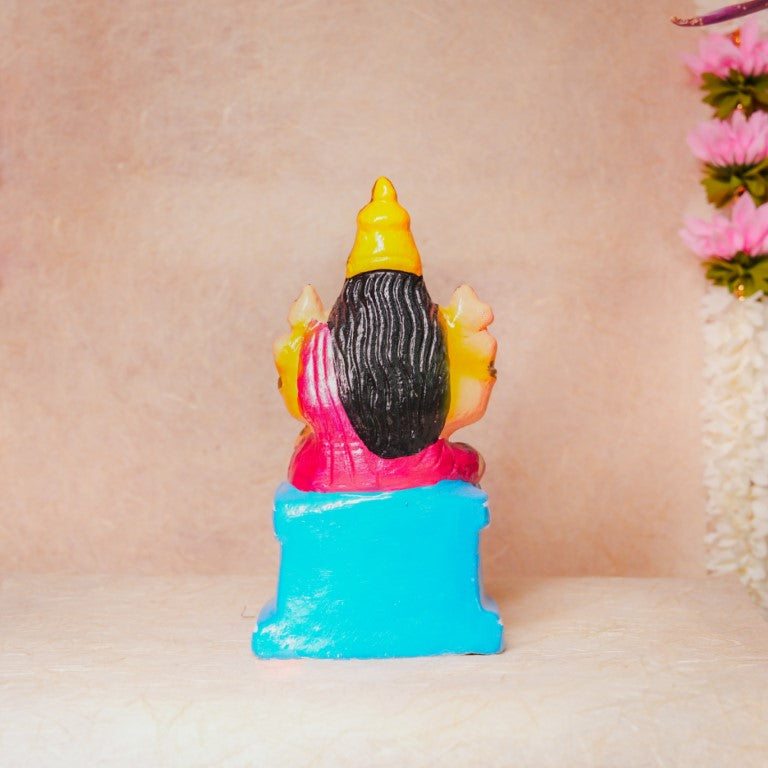 Hand-painted Navarathri Golu doll of Goddess Karumari Amman in a colorful seated posture with intricate detailing and vibrant pink and gold hues.