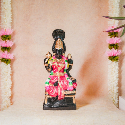 Handcrafted Navarathri Golu doll of Karumari Amman in vibrant pink attire, seated with traditional detailing, adorned with flowers.