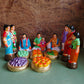 Handcrafted Navaratri Golu doll set featuring a Kadhu Kuthal (Ear Piercing) ceremony with family members, festive food platters, and ceremonial elements.