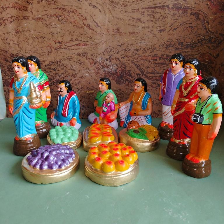Handcrafted Navaratri Golu doll set featuring a Kadhu Kuthal (Ear Piercing) ceremony with family members, festive food platters, and ceremonial elements.