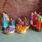 Handcrafted Navaratri Golu doll set featuring a Kadhu Kuthal (Ear Piercing) ceremony with family members, festive food platters, and ceremonial elements.