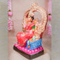 Handcrafted Bhuvaneshwari Amman Golu doll with vibrant colors and intricate throne design, displayed with floral decor.