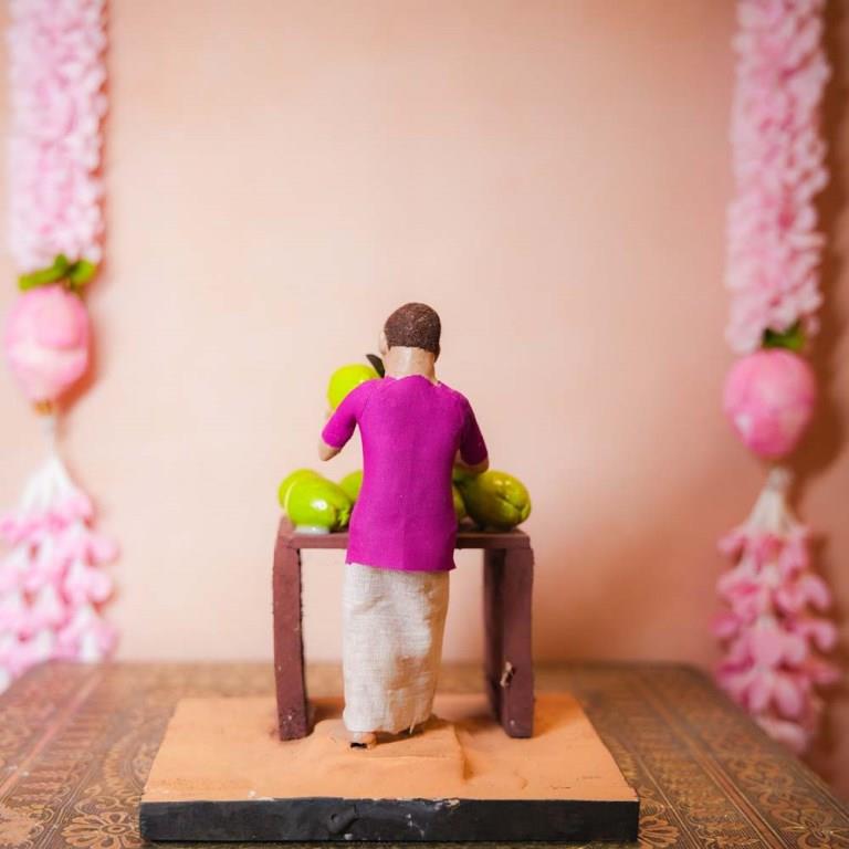 Handcrafted Golu Doll depicting a traditional coconut seller with fresh coconuts on a table, designed for Navarathri Golu.