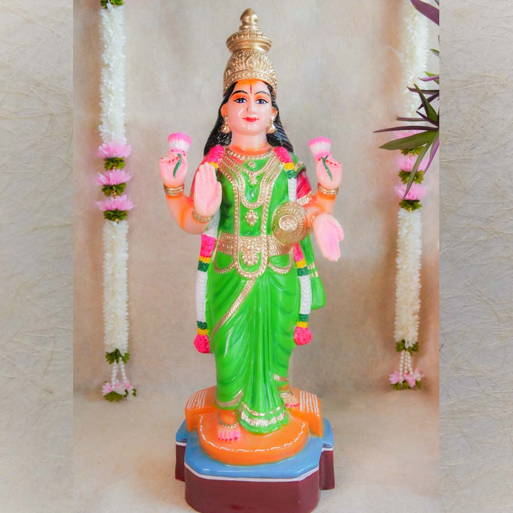 Handcrafted Vasthu Lakshmi idol in a green saree holding pink lotuses, designed for traditional Indian decor and puja purposes.