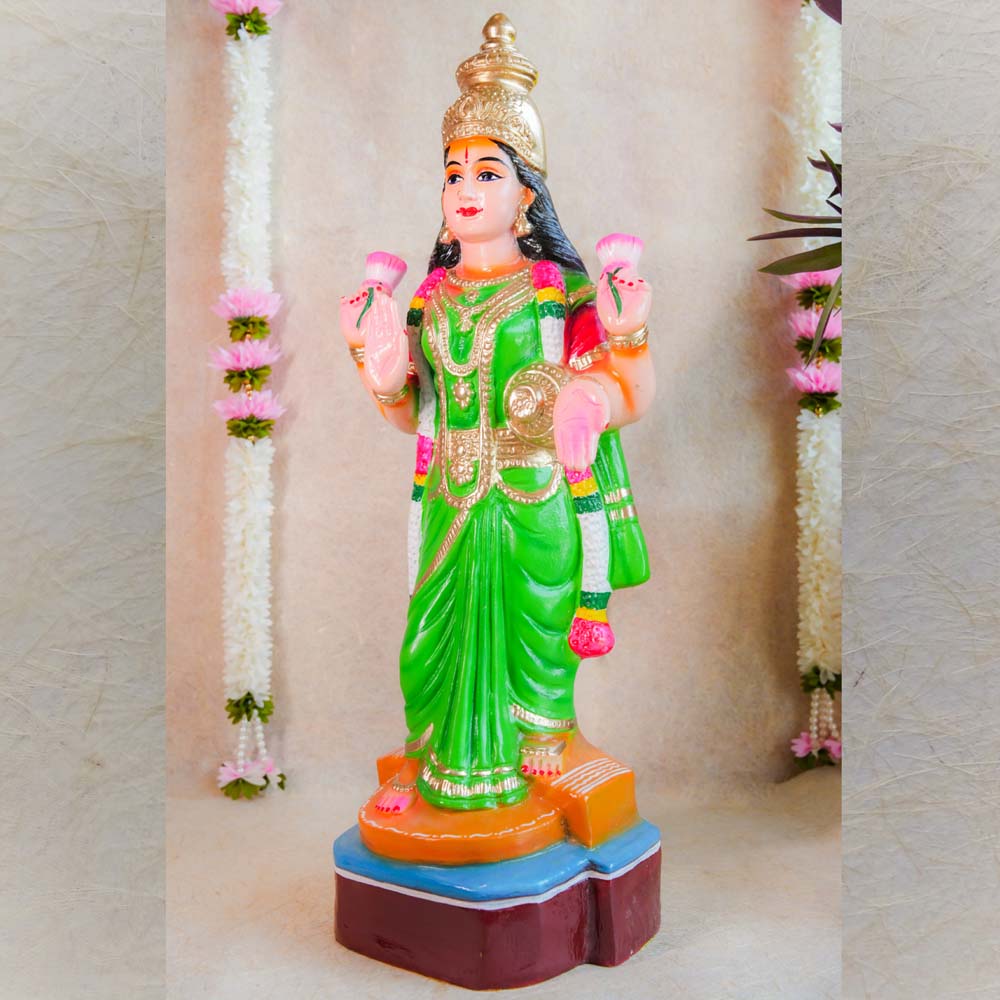 Handcrafted Vasthu Lakshmi idol in a green saree holding pink lotuses, designed for traditional Indian decor and puja purposes.