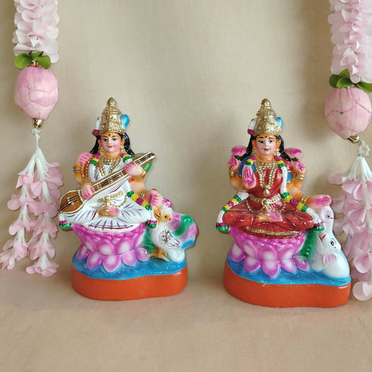 Handcrafted Lakshmi and Saraswathi Golu dolls set with vibrant colors, displayed with pink floral garlands.