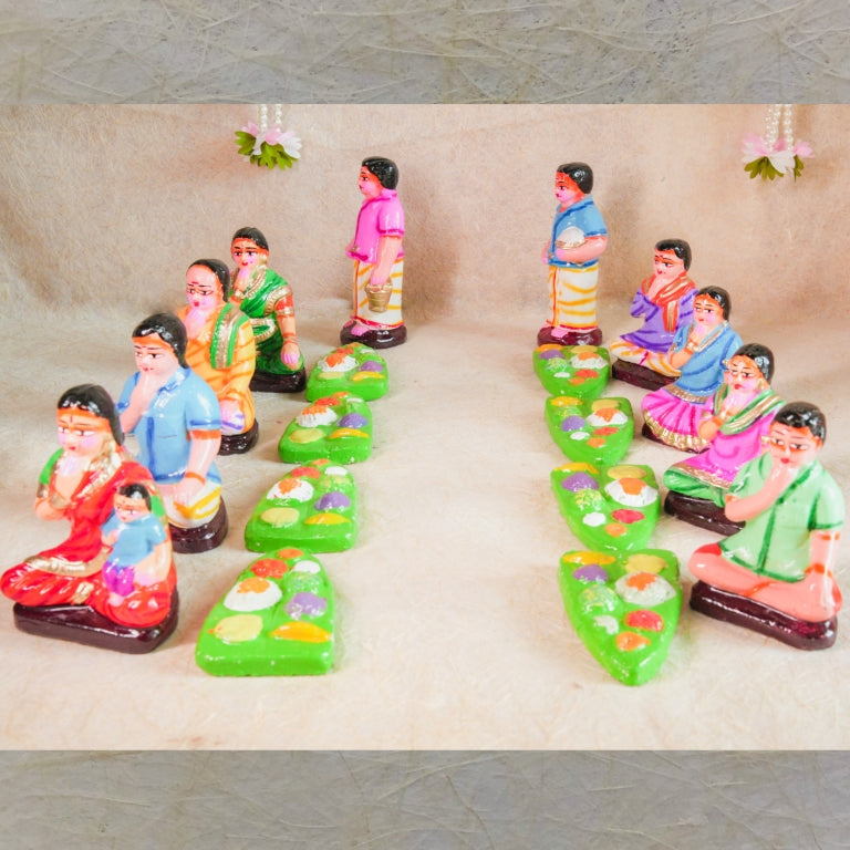 Handcrafted Navaratri Golu Sappadu Set featuring seated figurines enjoying a feast served on banana leaves, vibrantly painted and detailed.