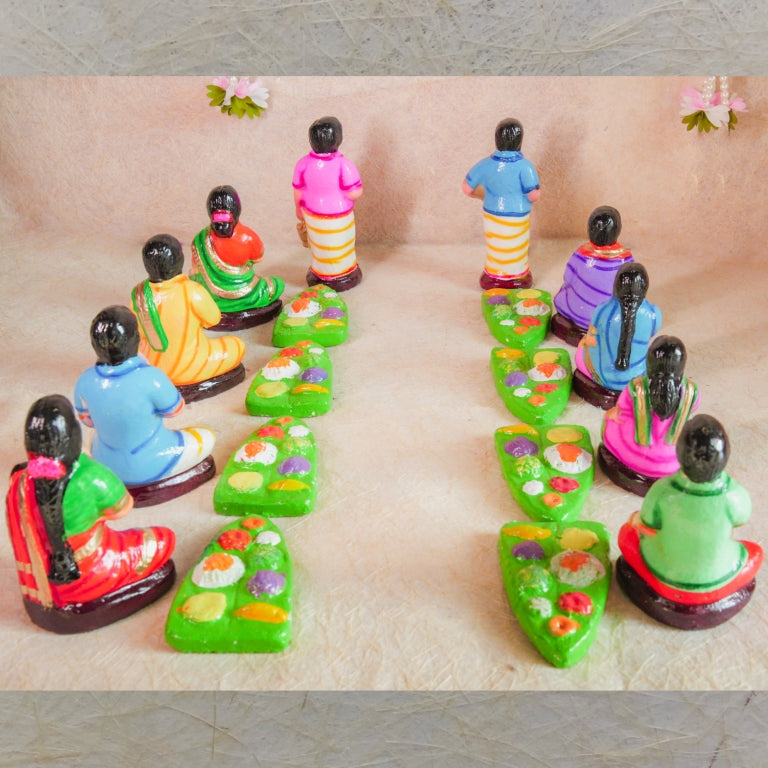 Handcrafted Navaratri Golu Sappadu Set featuring seated figurines enjoying a feast served on banana leaves, vibrantly painted and detailed.