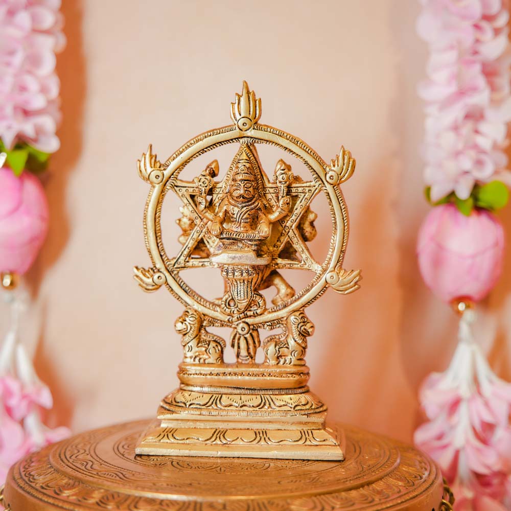 Chakrathalwar brass idol of Lord Vishnu with Sudarshana Chakra, displayed with floral decorations, showcasing intricate craftsmanship.