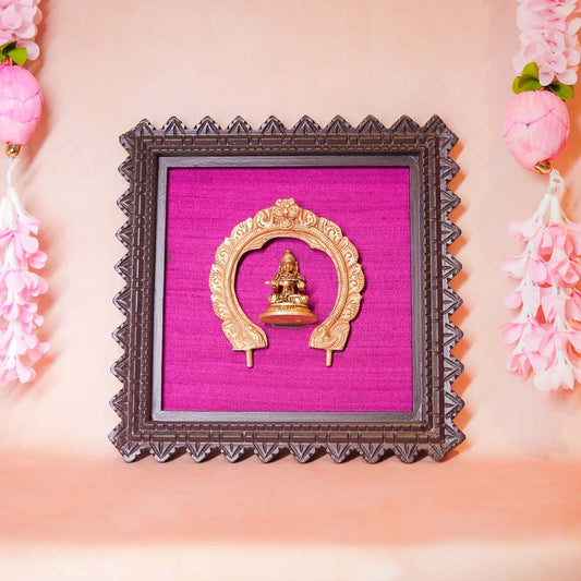 Framed brass sculpture of Goddess Annapoorni within an ornate Prabhavali, mounted on a purple fabric background with a carved wooden frame.