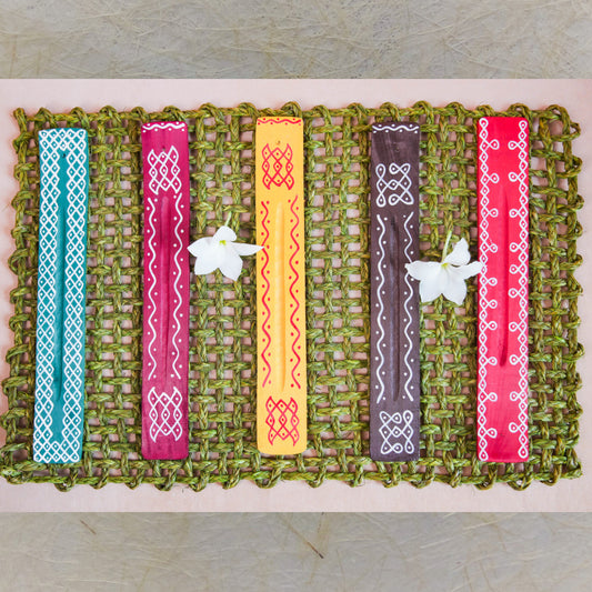 Handcrafted Kolam Incense Stick Holders with traditional Kollam art patterns, featuring vibrant colors on a woven green mat.