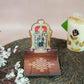 Meenakshi Diya Wall Stand featuring a vibrant depiction of Goddess Meenakshi with a kolam-patterned wooden base for holding oil lamps.