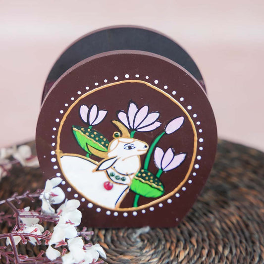 Hand-painted wooden penstand with a white cow design surrounded by lotus flowers, crafted on a brown background.