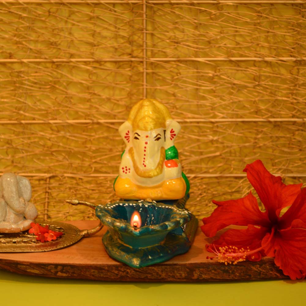Handcrafted Sitting Ganesha Agal lamp holder with a vibrant blue diya and intricate hand-painted details.