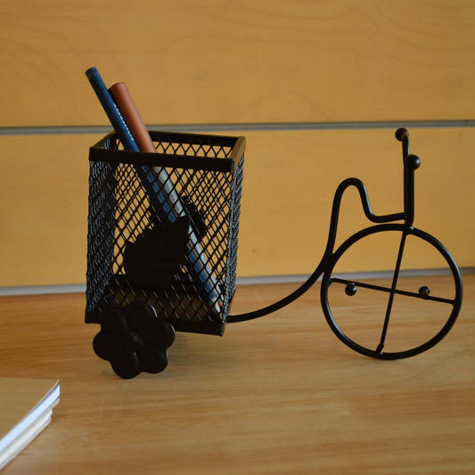 Metal cycle-shaped spoon and pen holder on a wooden surface with sleek black finish.