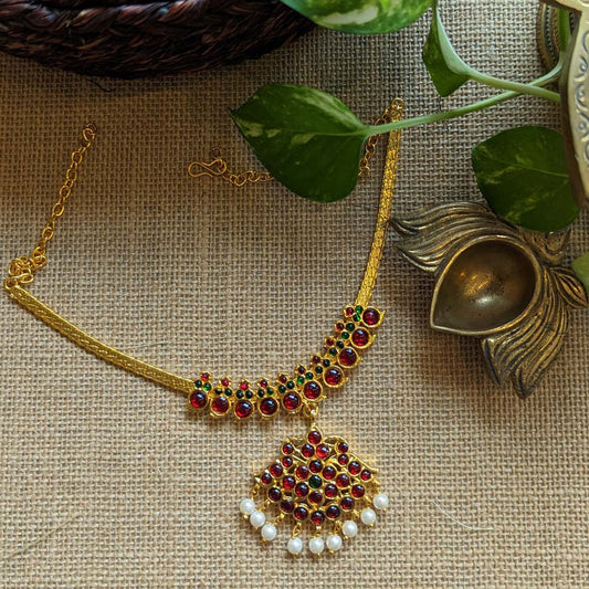 Short Kemp Necklace with gold chain, red and green Kemp stones, and pearl drop pendant on a burlap background