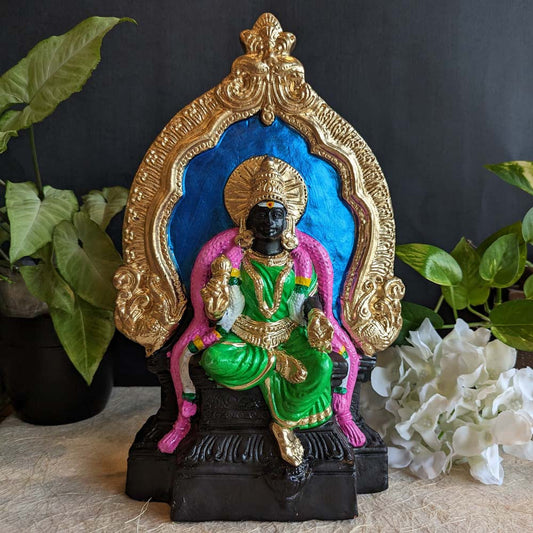 Handcrafted Goddess Meenakshi Golu doll seated on a throne with a golden ornate arch, dressed in green attire with a blue backdrop, perfect for Navaratri decor.