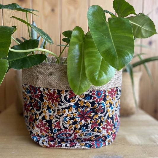 Natural jute plant holder with vibrant floral prints on a black background, designed for indoor plants and eco-friendly decor.