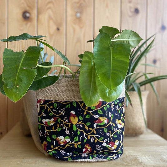 Natural jute plant holder with a vibrant bird print, perfect for indoor plants, combining rustic charm and modern design.
