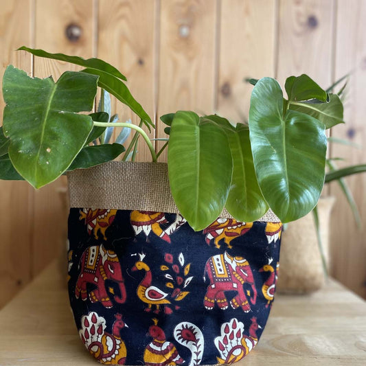 Natural jute plant holder with an intricate elephant and peacock print, suitable for indoor plants, blending rustic and artistic decor elements.