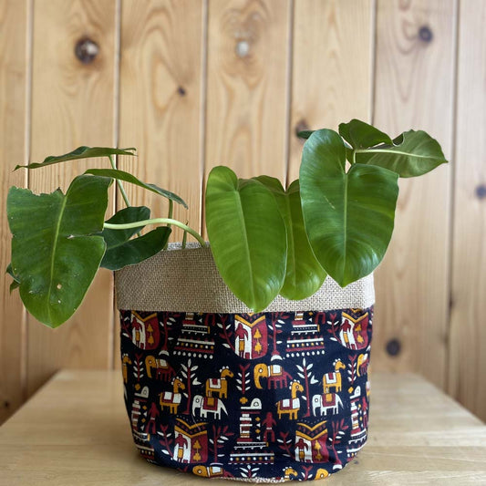 Natural jute plant holder with vibrant elephant and tribal print, suitable for indoor and outdoor plants, adding a rustic and cultural touch to any decor.