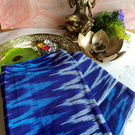 Pochampalli fabric in blue tones with a bold zigzag pattern, handwoven cotton blend, displayed with traditional decor.